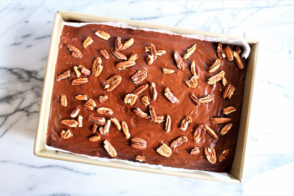 chocolate cake in pan with icing and pecans