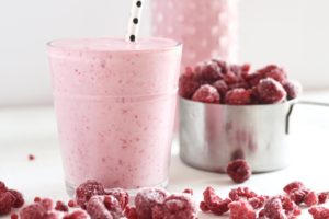 Easy no added sugar raspberry smoothie in a cup with raspberries in measuring cup