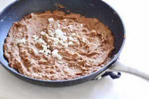 Semi-homemade Mexican refried beans in a skillet with cheese topping