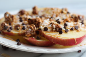 apple nachos on a plate with cacao nibs and peanut butter