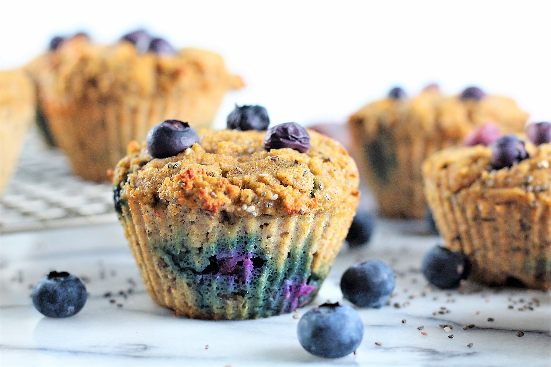 blueberry chia muffins | Milk & Honey Nutrition side view of blueberry chia muffins on countertop with blueberries