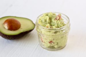small jar of guacamole for one with half of an avocado