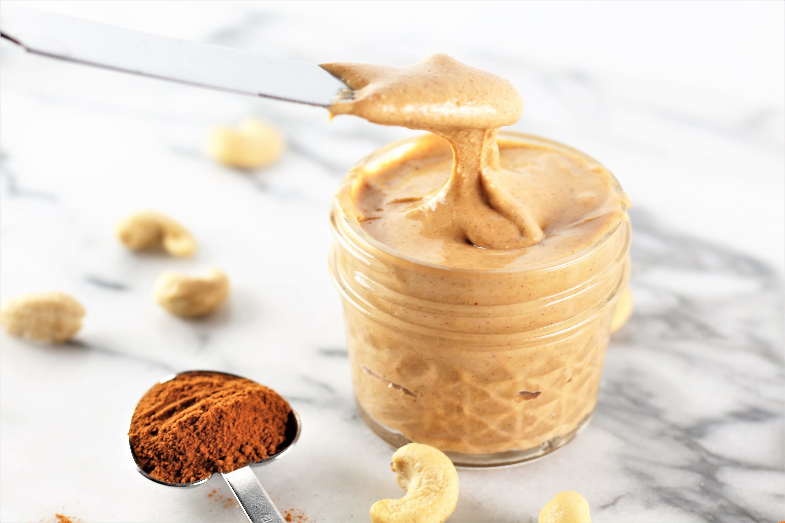 pumpkin spice roasted cashew butter with measurement of pumpkin spice on counter