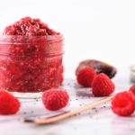 raspberry chia jam in a jar with raspberries on counter