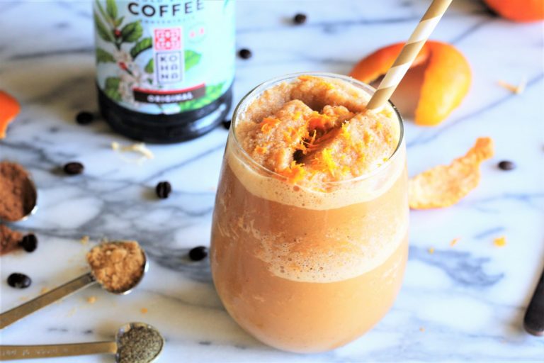 spiced orange frozen latte in glass cup with coffee in background