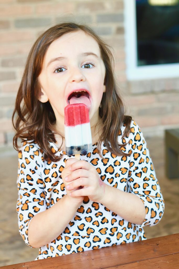 kid eating red white and blue popsicle