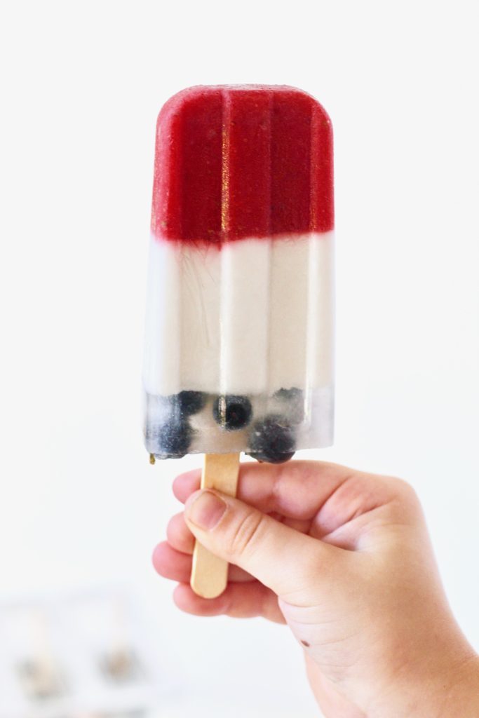 hand holding red white and blue fruit popsicle