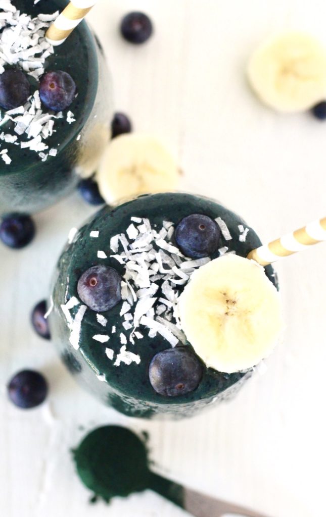 Spirulina smoothie with coconut flakes banana and a paper straw