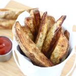 potato wedges in white bucket with ketchup