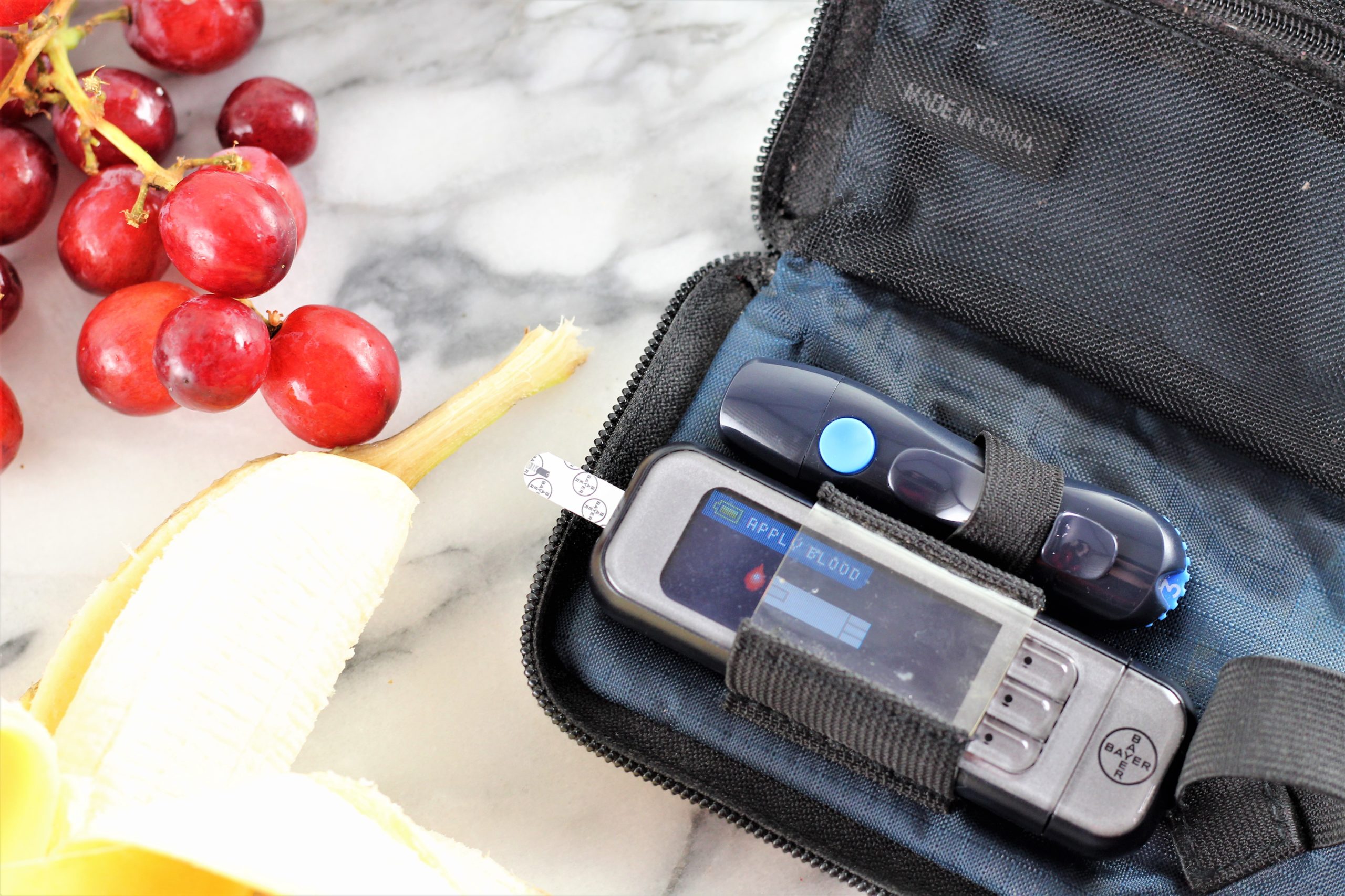 blood glucose meter with bananas and grapes for blood sugar balance