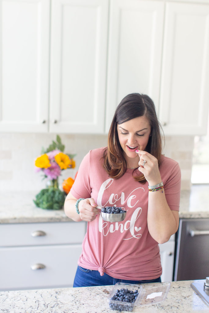 woman in pink shirt eating blueberries