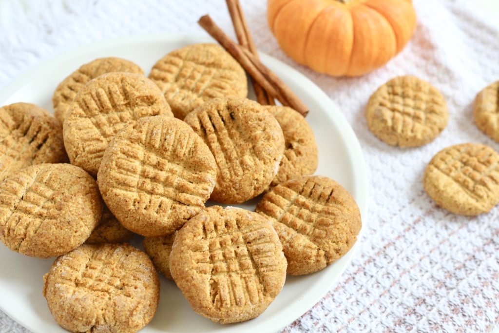 pumpkin cookies on white plate with cinnamon sticks and mini pumpkin