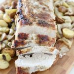 pork loin roast with onions and potatoes on wooden cutting board