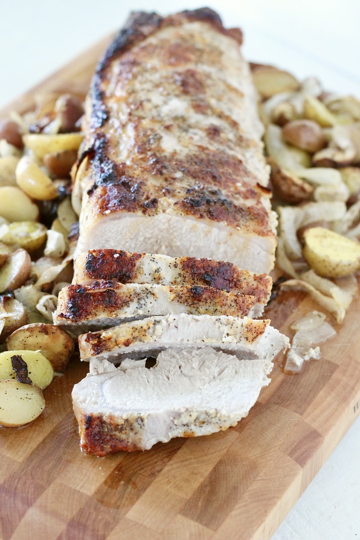 pork loin roast with onions and potatoes on wooden cutting board