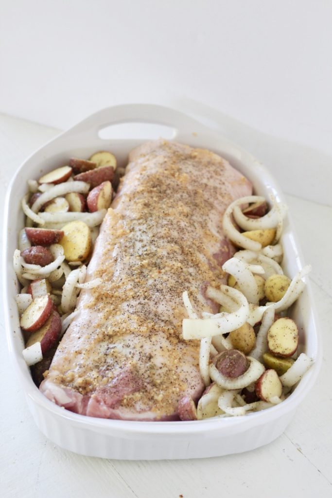 raw pork loin in pan with potatoes and onion