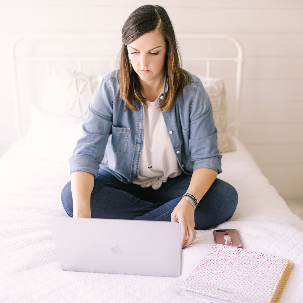 woman working on computer sitting on bed