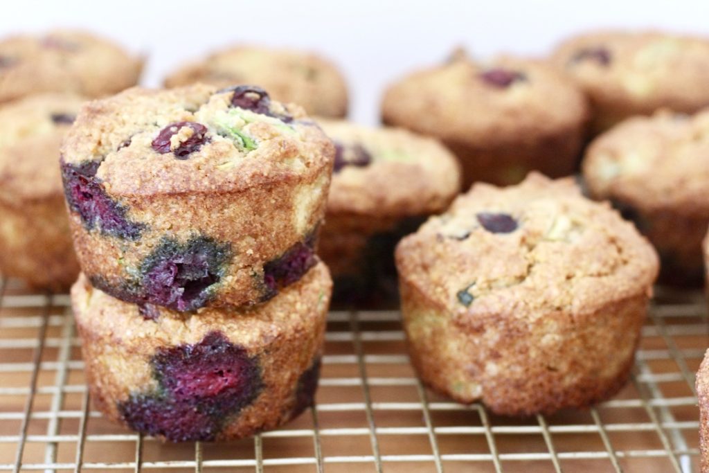 blueberry zucchini muffins on wood chopping block