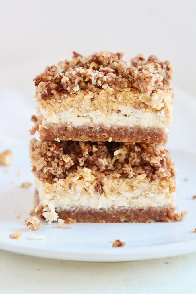 Gluten-Free Pumpkin Cheesecake Bars with Oatmeal Crust 7 | Milk & Honey Nutrition layered pumpkin cheesecake bars stacked on top of each other