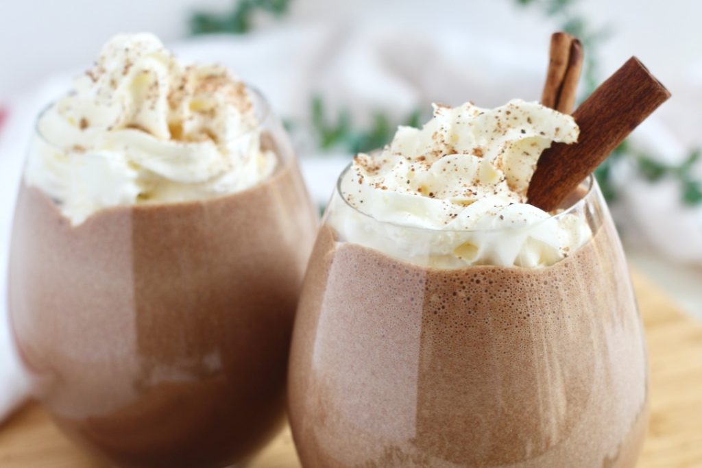 chocolate eggnog with whipped cream and cinnamon sticks