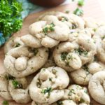 gluten free garlic knots with [arsely on wooden cutting board