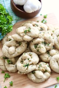 gluten free garlic knots with [arsely on wooden cutting board