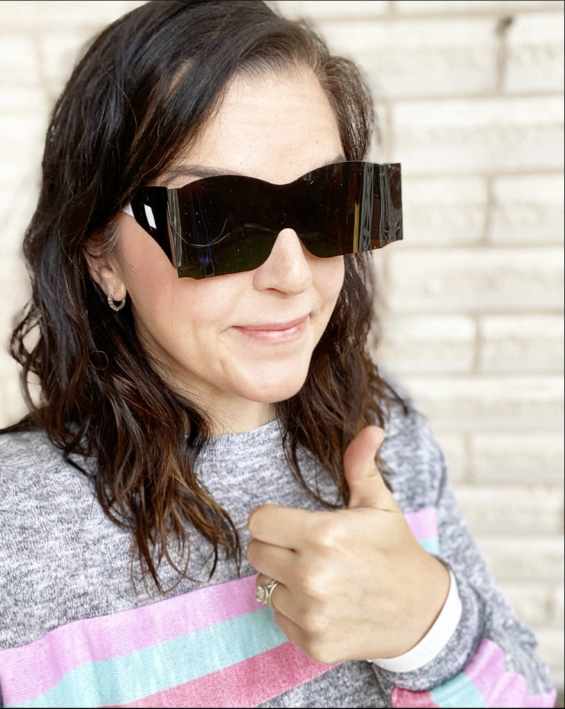 woman after routine eye exam with plastic sunglasses and thumbs up