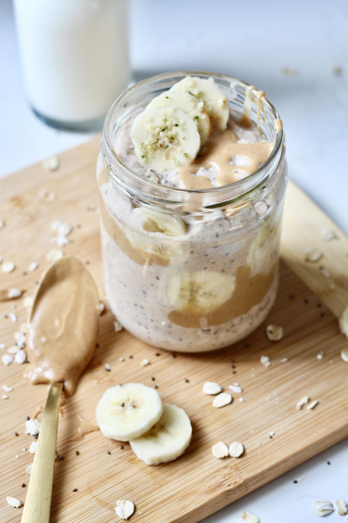 banana peanut butter overnight oats in glass jar with gold spoon of peanut butter made with kefir