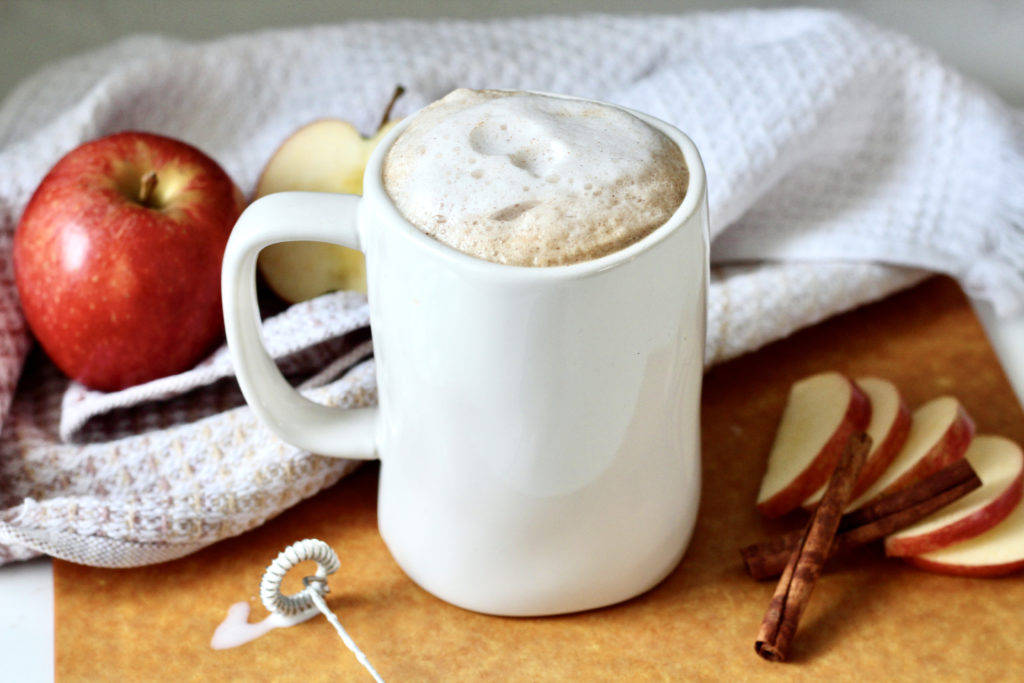apple crisp macchiato with sliced apples | Milk & Honey Nutrition apple crips macchiato with sliced apple and stick frother in white mug