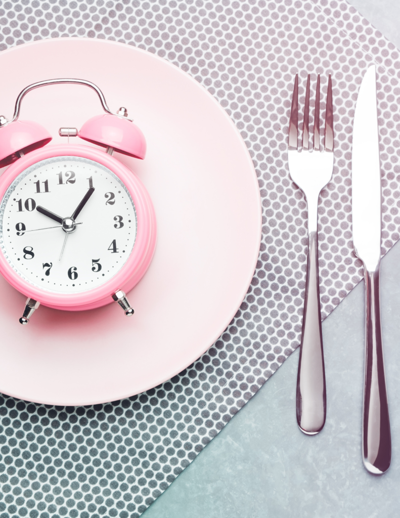 pink alarm clock on pink plate with silver fork and knife for intermittent fasting and diabetes
