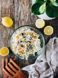 low carb coleslaw in clear bowl with lemons