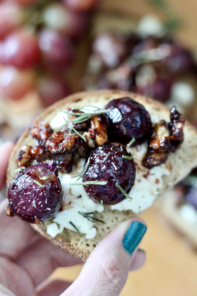 woman holding roasted grapes on toast