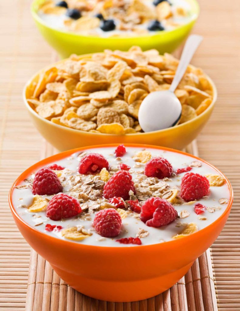 bowl of cereal with milk and raspberries