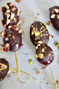 dark chocolate covered grapes with nuts on skewers