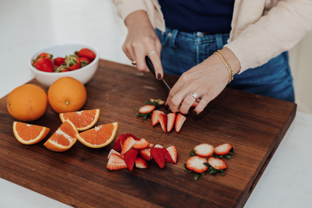 wooden cutting board chopping strawberries and oranges